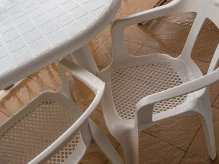 Rain-soaked chairs and table on an empty terrace of an apartmentの写真素材