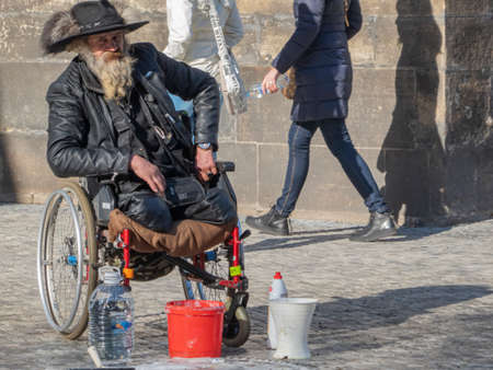Prague, Czech Republic; February 16 2019. Homeless beggar in a wheelchair preparing soap to make bubbles in Prague.のeditorial素材