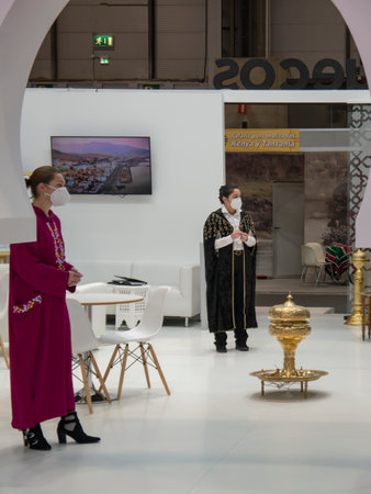 Madrid, Spain; January 19 2022. Two female assistants standing at the Moroccan stand in FITUR (International Tourism Trade Fair). Photography taken on January 19, 2022 in Madrid, Spain.のeditorial素材