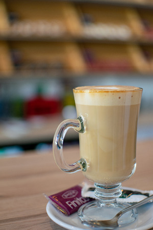 a cafÃ© latte with donut shelves in the backgroundの写真素材