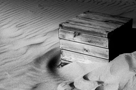a weathered wooden box being consumed slowly by sand at the beach of Bolonia, Spainの写真素材