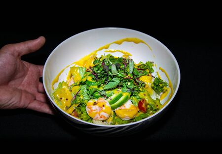 a tasty prawn and avocado salad being presented by a hand