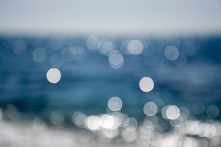 a out of focus shot of my local beach in Marbella with the sun shimmering of the water and the clouds in the backgroundの写真素材