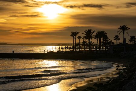 a golden beach scene of a sunset setting in Marbella, Spainの写真素材