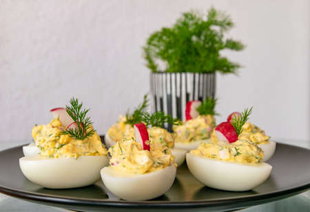 a selection of freshly made stuffed boiled eggs set out on a plate garnished with organic dillの写真素材