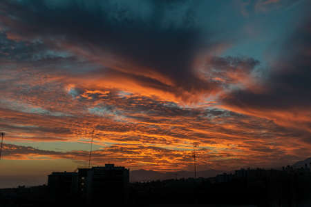 the last golden clouds being lit from behind a silhouetted cityscape in Marbella, Spain