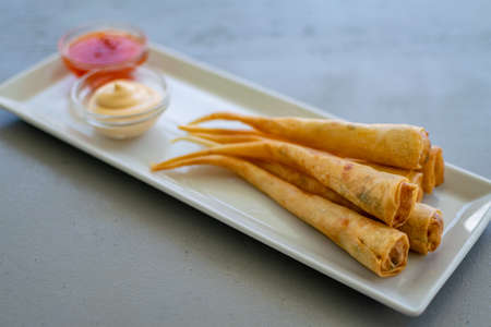 a plate of delicious prawn spring rolls served with dipping sauces on a bar along the Mediterranean coastlineの写真素材
