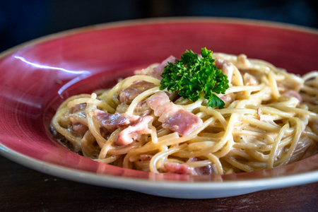 a freshly prepared spaghetti carbonara served in a red bowl close upの写真素材