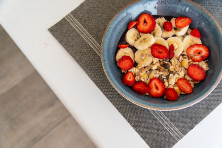 a bowl of freshly prepared acai ice cream topped with fresh fruit and oatmeal on a tableの写真素材