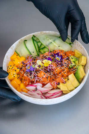 a portrait image of a chef presenting a freshly made salmon poke bowl