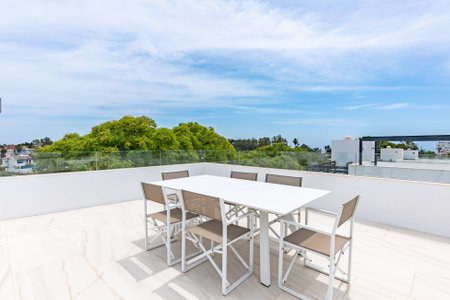an image from a rooftop terrace with large white dining table in mediterranean real estate propertyの写真素材