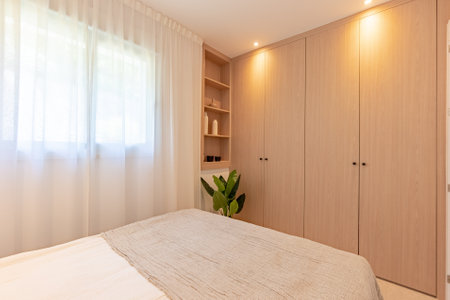 a small guest bedroom with fitted wooden closet and shelving in mediterranean hotel roomの写真素材