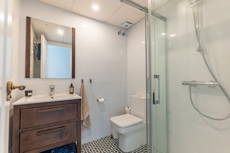 an image of a simple bathroom with standing shower and wooden cabinet in holiday apartmentの写真素材