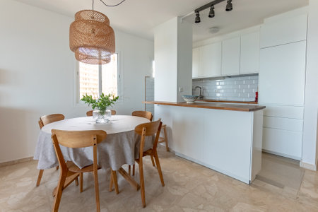 a dining table with wooden chairs next to wooden countertop kitchenの写真素材
