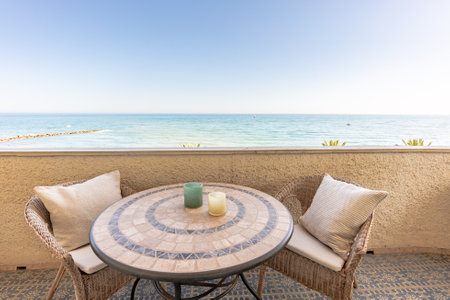 a close up image of a small table and chairs overlooking the mediterranean sea from beachfront apartmentの写真素材