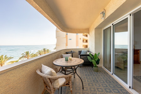 an image of a luxury beachfront apartment terrace with table and chairs overlooking the mediterraneanの写真素材