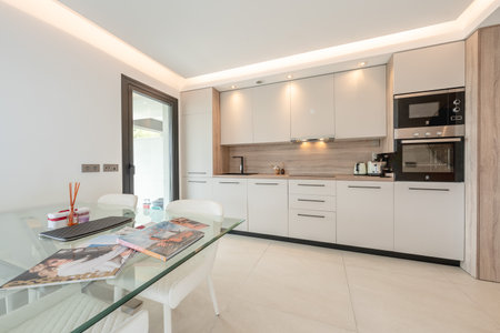 an image of an open illuminated kitchen and dining room in mediterranean holiday homeの写真素材