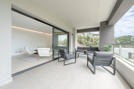 an image of a luxury apartment terrace with open glass door to living roomの写真素材