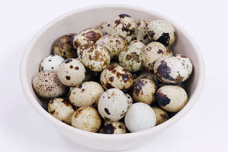 fresh quail eggs isolated on white background in a basketの写真素材