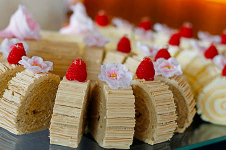 swiss roll cake slices decorated with berries and edible flowersの写真素材