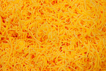 grated red cheddar cheese in close upの写真素材