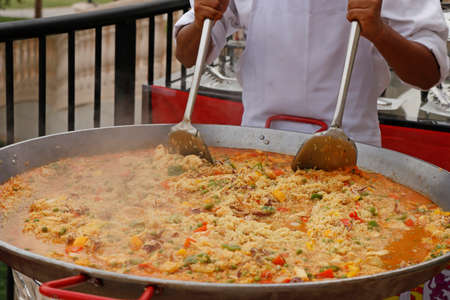 chef cooking spanish paella in outdoor areaの写真素材