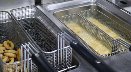 crispy french fries in a deep fat fryer with steel net basketの写真素材