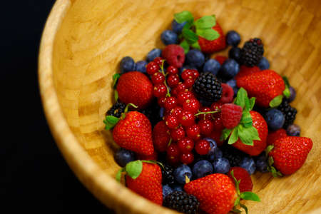 fresh berries fruit in wooden bowl includes strawberry, raspberry,blue berry,black berry etc.の写真素材
