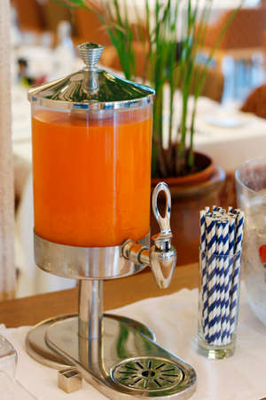 Fruit juice dispenser with paper straw on a self service breakfast counter in a hotel restaurantの写真素材