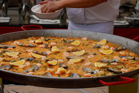 chef cooking spanish paella in outdoor areaの写真素材