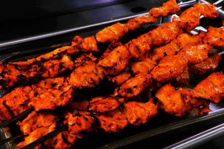 spice marinated chicken cubes ( chicken tikka )skewers cooking in a clay oven known as tandoorの写真素材