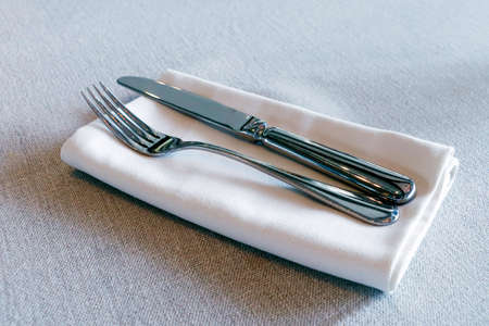 restaurant cutlery, knife and fork on a table with white napkin