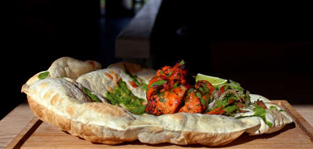chicken tikka with naan bread on a wood boardの写真素材