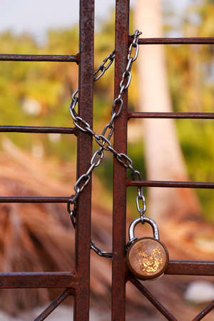 padlock and strong steel chain wrapped around the metal entrance gateの写真素材