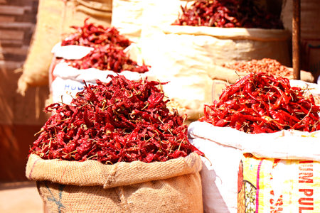 fresh whole dry red chilies stored in bag for sell in a market stallの写真素材