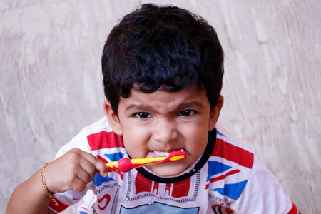adorable cute indian baby boy with colorful shirt doing morning brushing the teethの写真素材