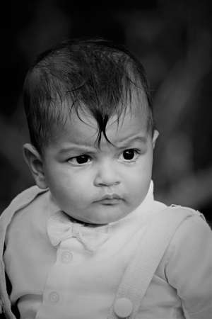 young indian baby boy looking very seriously in close up portraitの写真素材