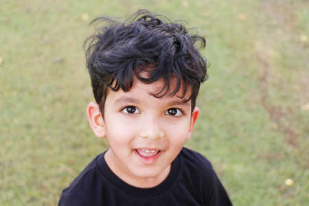 cute boy kid in close up look with black shirt in a fieldの写真素材