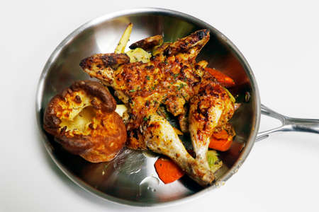 oven roasted or baked marinated baby chicken with vegetables and yorkshire pudding served in a metal panの写真素材