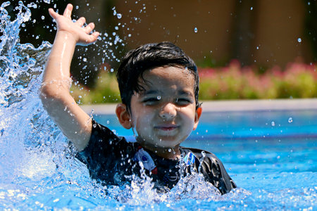 young boy enjoying in swimming pool, water splashingの写真素材