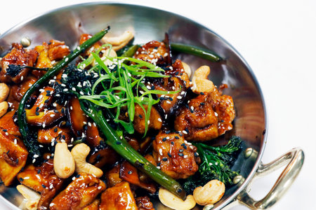 wok fried chinese chicken with broccoli, bok choy and cashew nut in soy sesame oyster sauce and white backgroundの写真素材