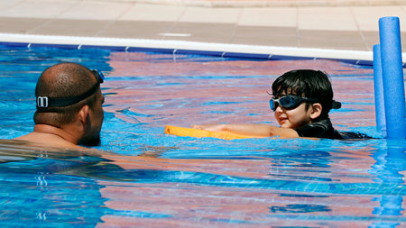 Dubai, United Arab Emirates â August 18, 2022 swimming teacher or trainer giving lesson to a student in a poolのeditorial素材