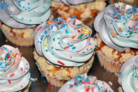 rainbow frosted vanilla flavored cupcake or muffin with sprinklesの写真素材
