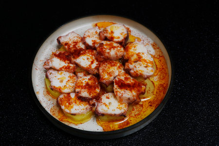 polpo alla gallega, is a popular spanish tapas dish with slow cooked octopus and boiled potato, paprika and olive oilの写真素材
