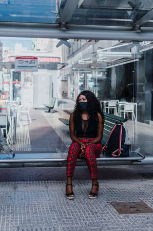 African girl sitting on bus stop bench waiting to be picked upの写真素材