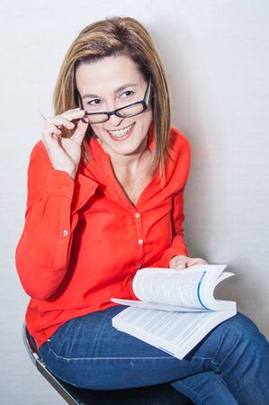 Very attractive and pretty Spanish woman wearing a red shirt, a book and glasses. study and businessの写真素材