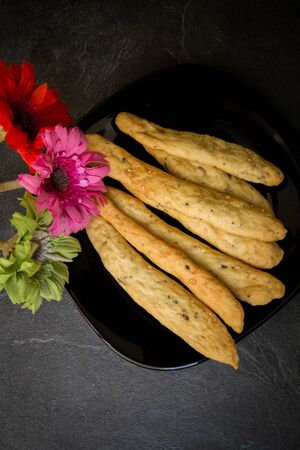 still life of pancakes, bagels, donuts with flowers on a black backgroundの写真素材