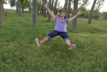 Old lady grandmother, old person, very funny jumping on the park grass laughing