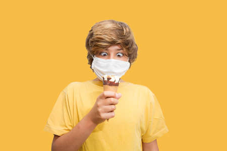 A boy holding ice cream while wearing a maskの写真素材