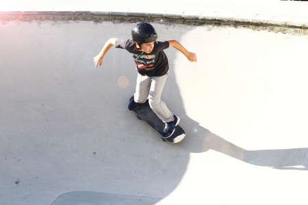 Child performs exercises and tricks in a flowing skate bowlの写真素材